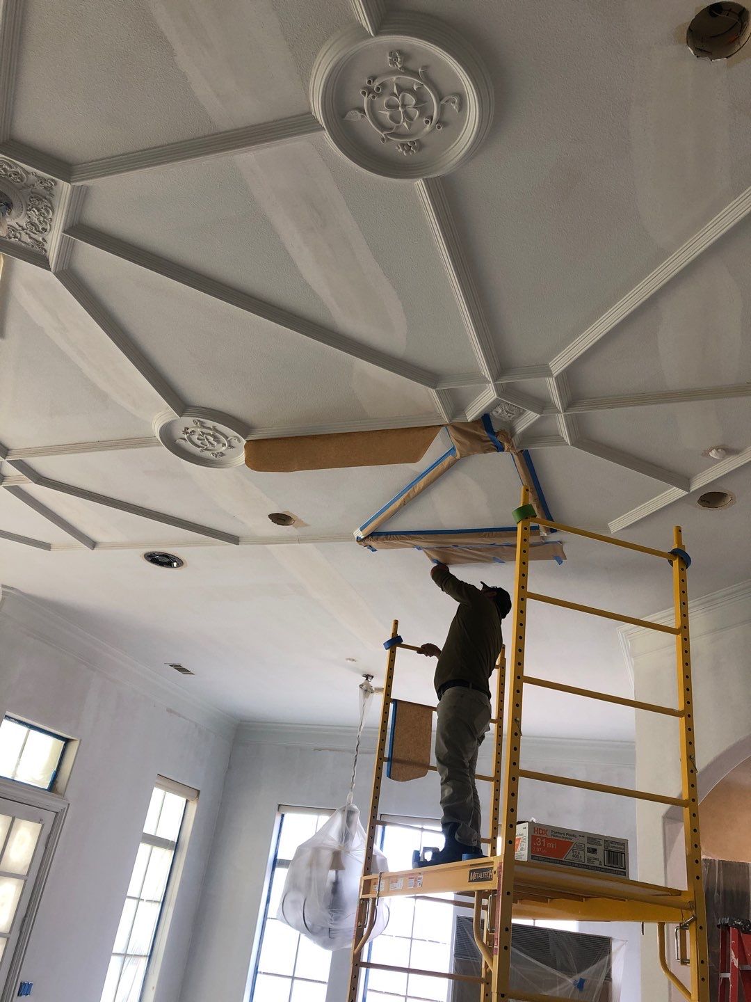 Craftsperson executing detailed ceiling work during a complex residential renovation