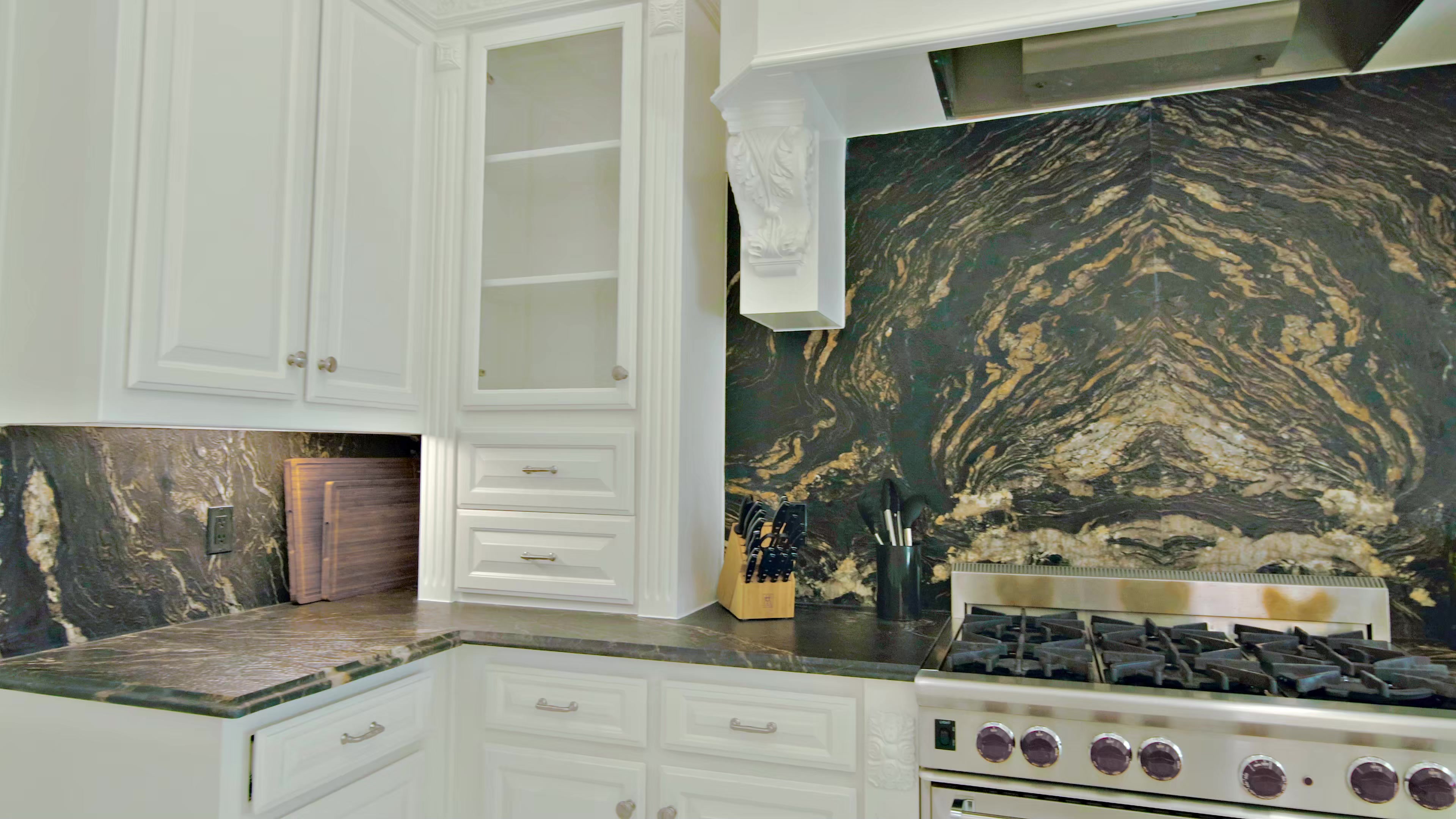 Kitchen from the JH Design project, with white cabinetry and dramatic dark stone behind the range