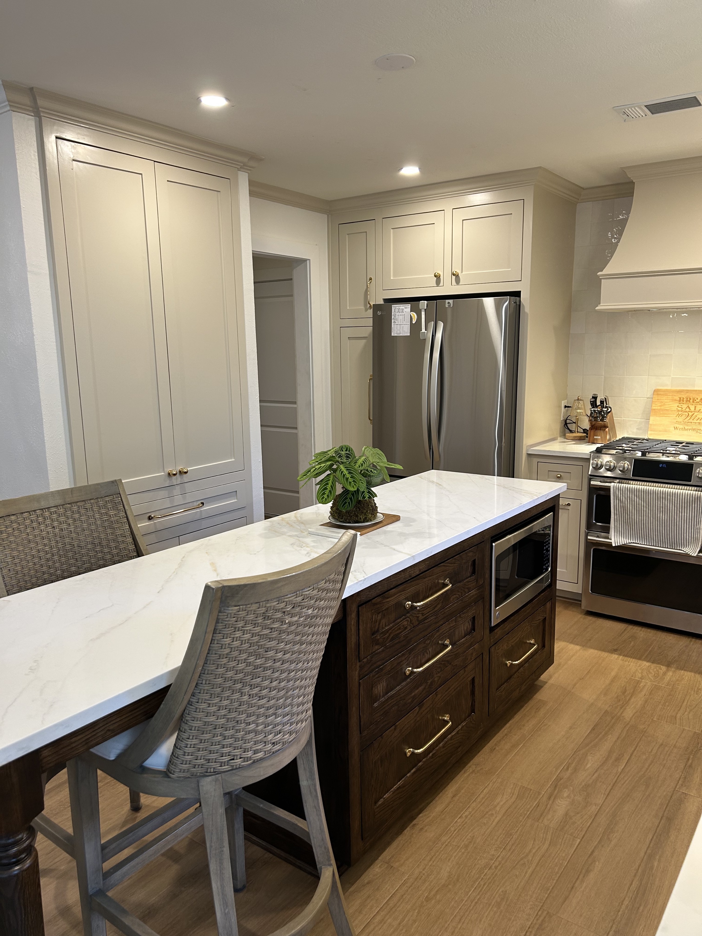 Completed kitchen island with dark wood cabinetry, a light stone countertop, and surrounding painted cabinets