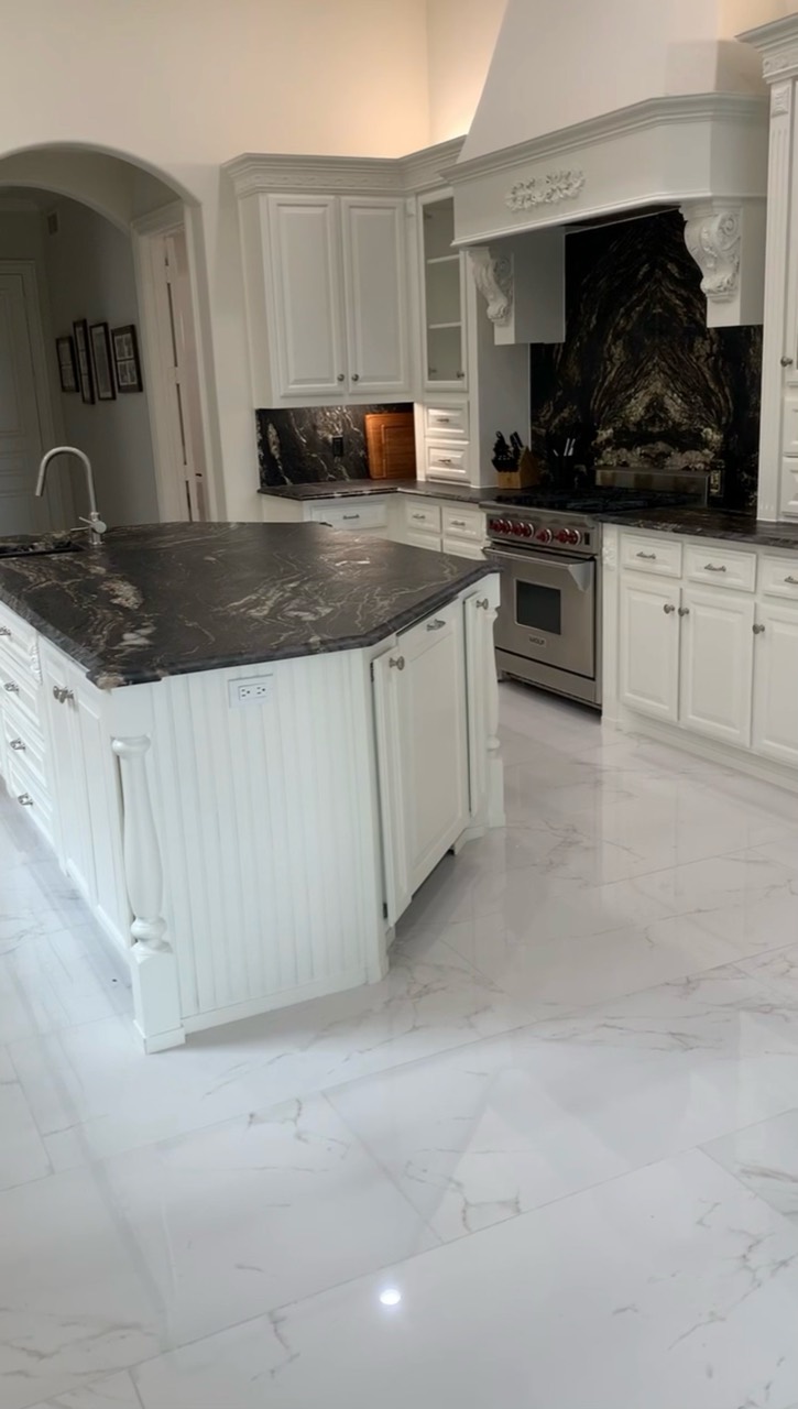 Completed white kitchen with a dark stone island and matching range surround